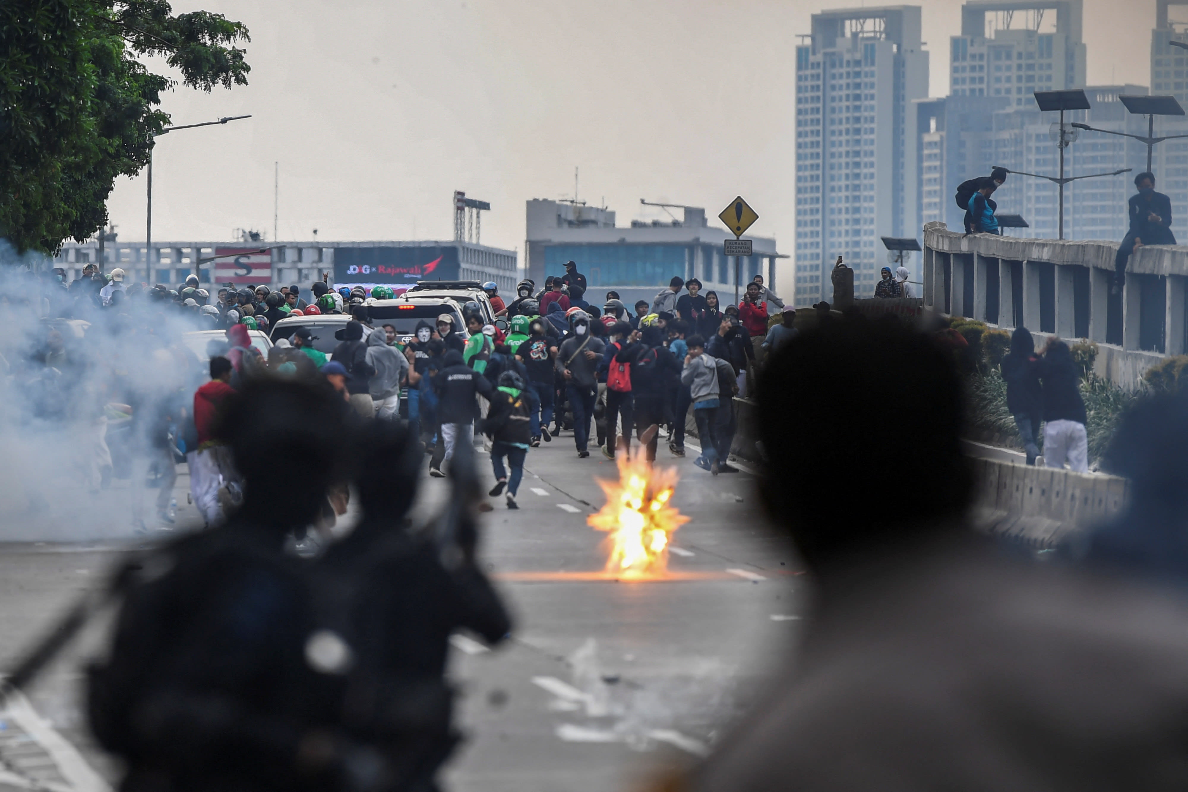 Protesters run away as riot police officers fire tear gas, during a rally against proposals floated by some ministers to extend Indonesian president Joko Widodo's term and postpone the 2024 election, near the Parliament building in Jakarta, Indonesia on April 11, 2022. 
