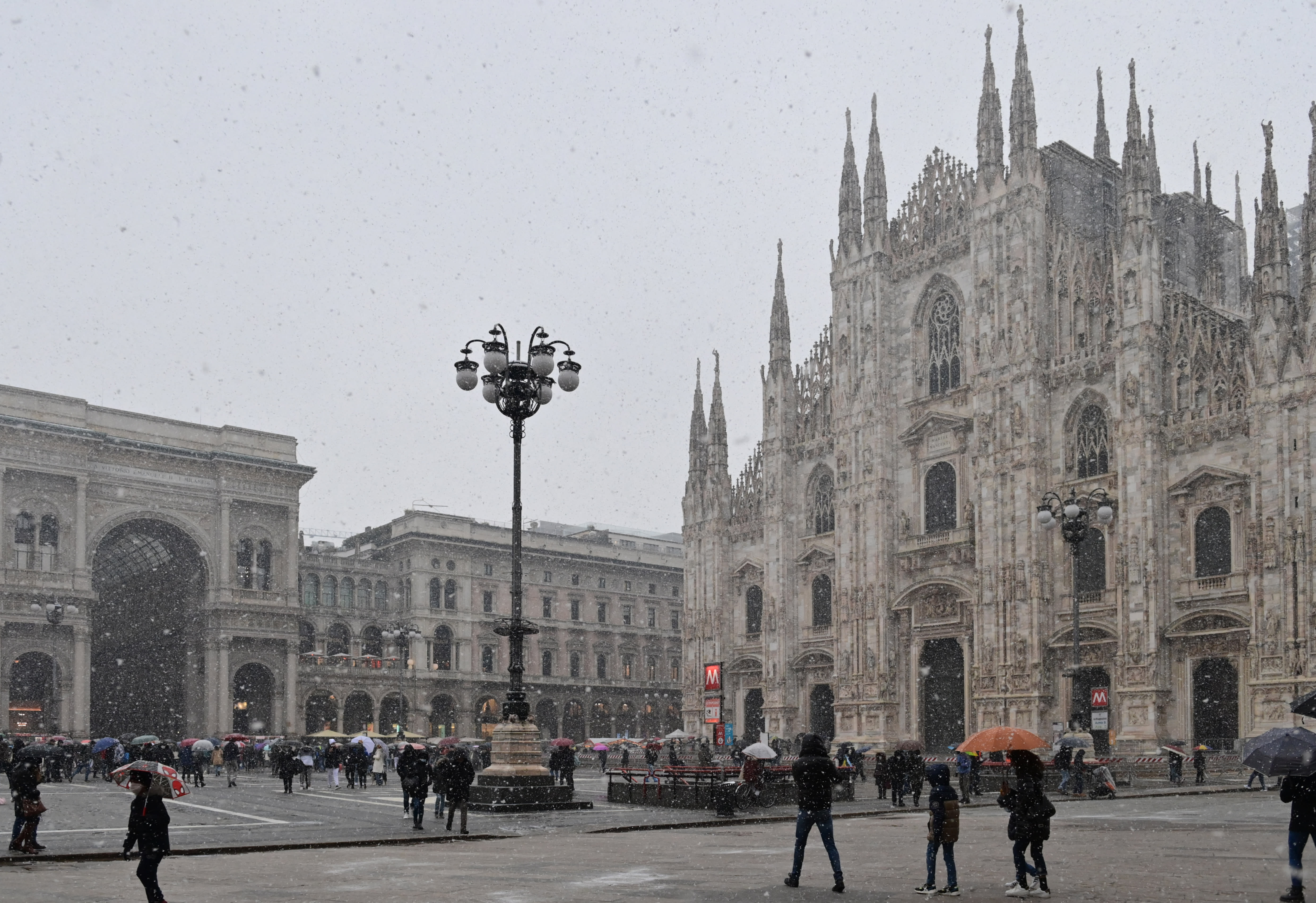 People walking across Piazza del Duomo past the cathedral as snow falls in Milan on Dec 8, 2021.
People walking across Piazza del Duomo past the cathedral as snow falls in Milan on Dec 8, 2021.