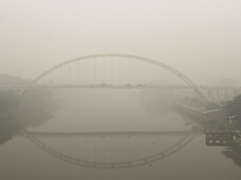 Vehicles drive across a bridge over Siak river in the haze-covered city of Pekanbaru, Riau province, on the island of Sumatra. The smoke has made tens of thousands of people sick. Photo: Reuters