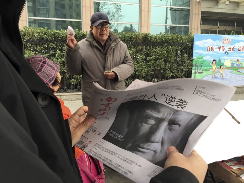 A Chinese man holds up a Chinese newspaper with the front page photo of US President-elect Donald Trump and the headline "Outsider counter attack" at a newsstand in Beijing. Photo: AP