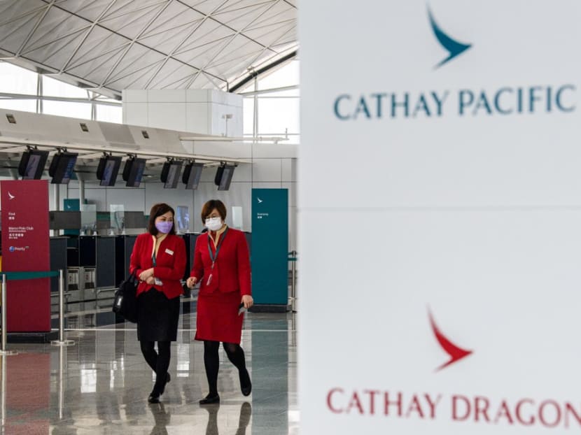 Employees walking past signage for Cathay Pacific near the flagship carrier's check-in counters at Hong Kong International Airport on Oct 20, 2020.
