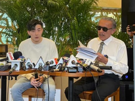 A Singaporean tourist who identified himself as “Sky” (left) discusses an alleged police extortion incident at the Davis Bangkok Hotel with former politician turned whistleblower Chuvit Kamolvisit (right) on Feb 1, 2023.