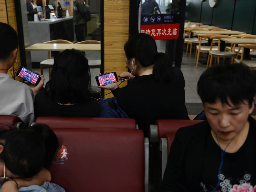 People watching a speech by Chinese President Xi Jinping on their mobile phones at a railway station in Beijing on Oct 1, 2019.