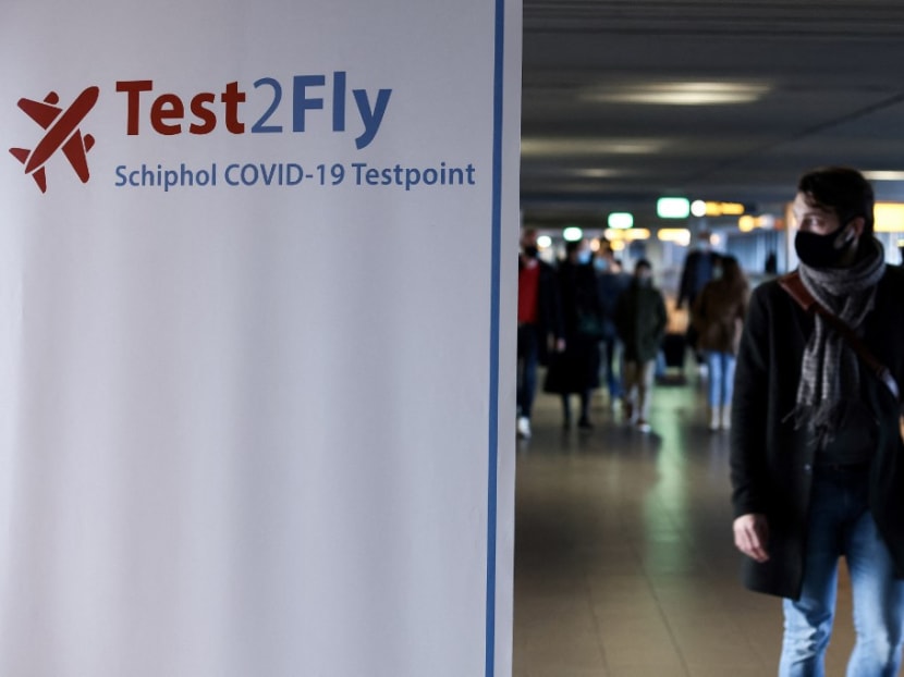 A passenger walks past a sign displaying the way to a Covid-19 test centre at the Schiphol airport on Nov 29, 2021.