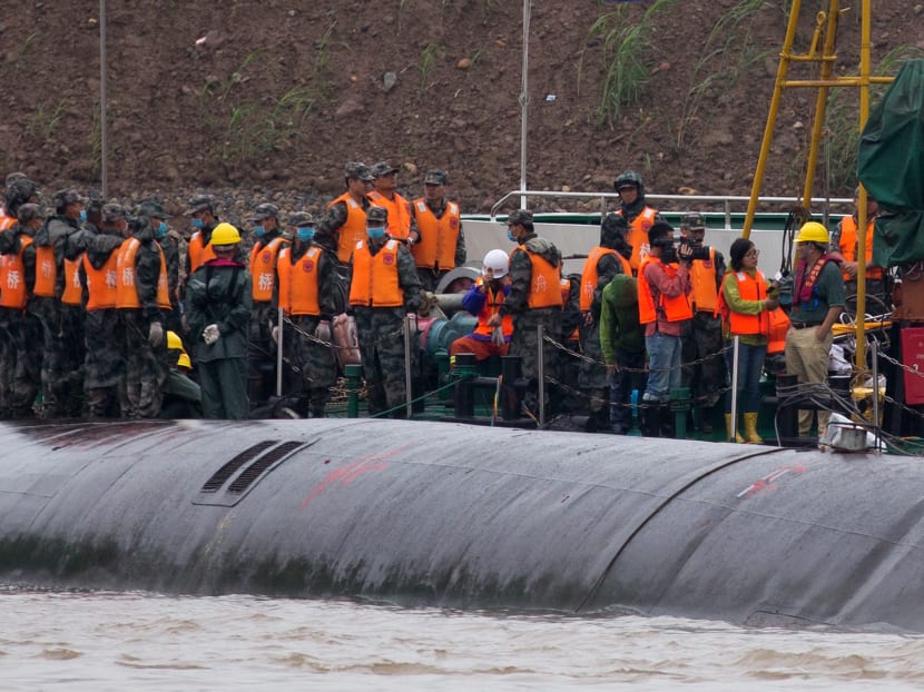 Chinese soldiers stand near a wrapped body as rescuers work on the capsized ship, center, on the Yangtze River in central China's Hubei province Wednesday, June 3, 2015. Photo: AP