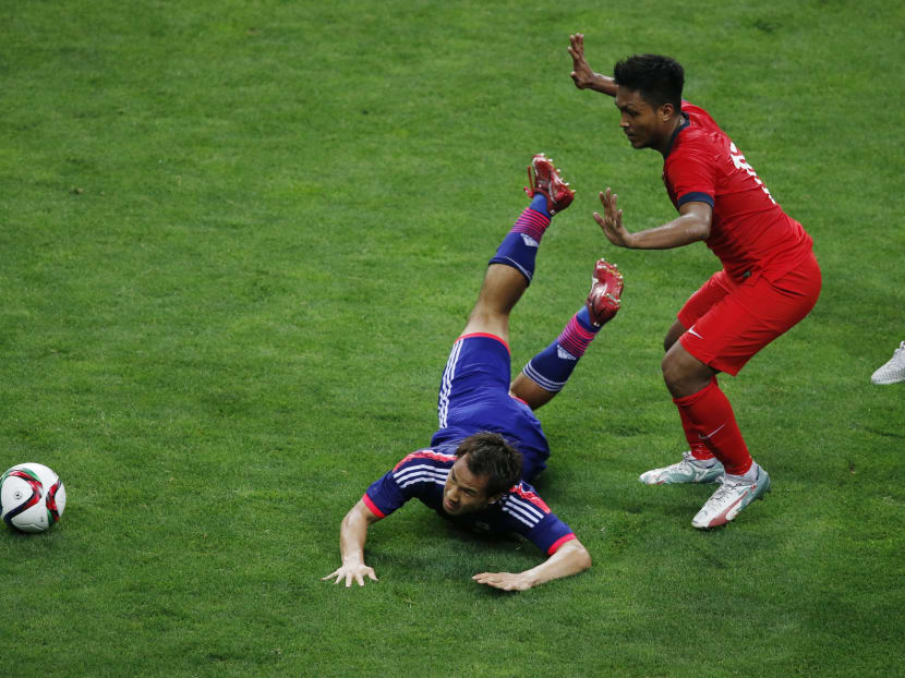 Japan’s Shinji Okazaki, left, loses the ball possession against Singapore's Ismadi Bin Muhamad Mukhtar during their second round soccer match of regional qualifiers for the 2018 World Cup, in Saitama, north of Tokyo, Tuesday, June 16, 2015. Photo: AP