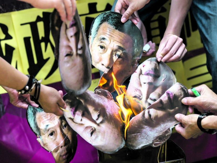 Protesters burning pictures of Mr Lee Kuan Yew and Mr Lee Hsien Loong outside the Singapore Consulate in Hong Kong yesterday. Photo: Reuters
