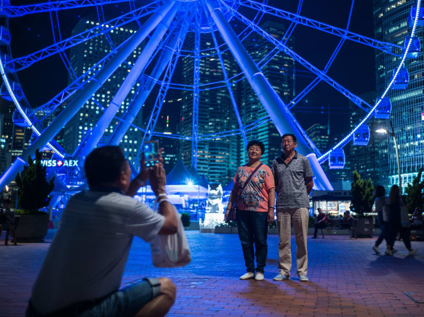 Chinese mainland tourists pose in front of a ferris wheel in the Central district of Hong Kong on Sept 21, 2016. Photo: AFP