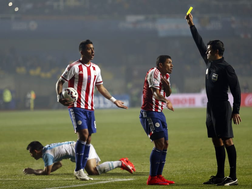 In this  June 30, 2015, file photo, referee Sandro Ricci, from Brazil, shows a yellow card to Paraguay's Richard Ortiz after he fouled Argentina's Sergio Aguero, right, during a Copa America semifinal soccer match at the Ester Roa Rebolledo Stadium in Concepcion, Chile. Photo: AP