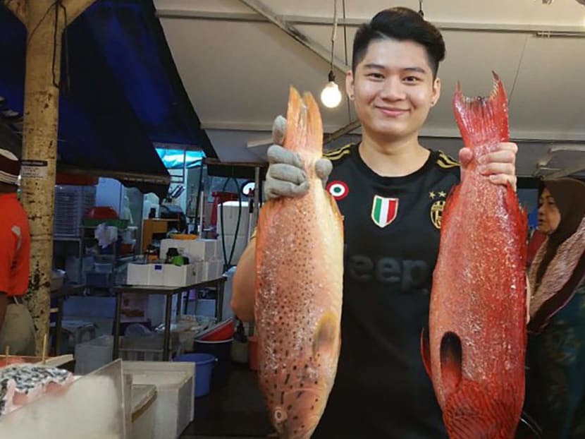 Mr Liew Rhui Heng, 23, posing with two large fish at the Jurong West wet market.