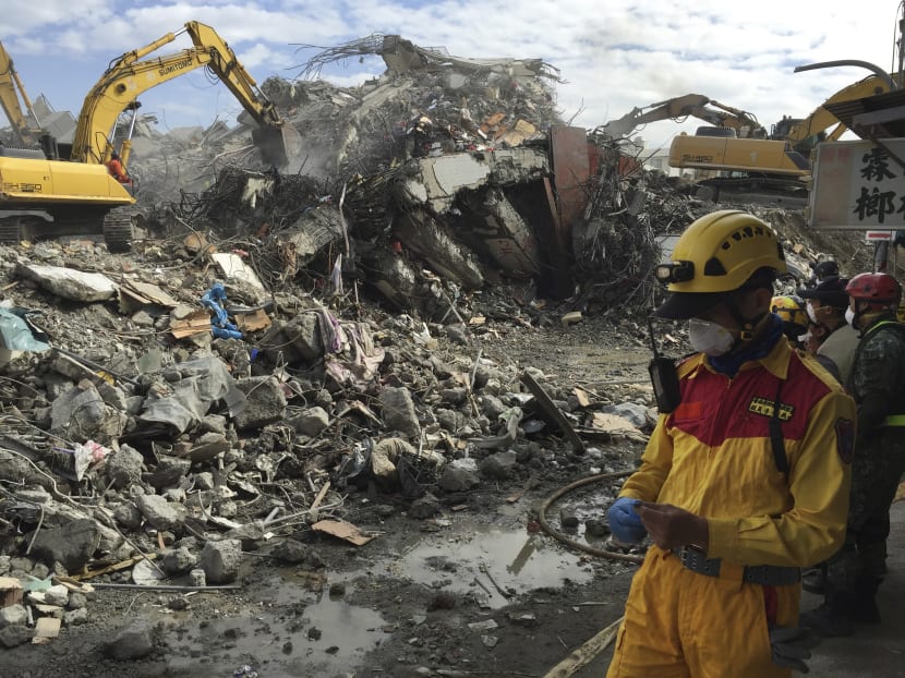 Rescue teams stand by as heavy excavation machinery continues to dig through the rubble of a collapsed building complex in Tainan, Taiwan. Photo: AP