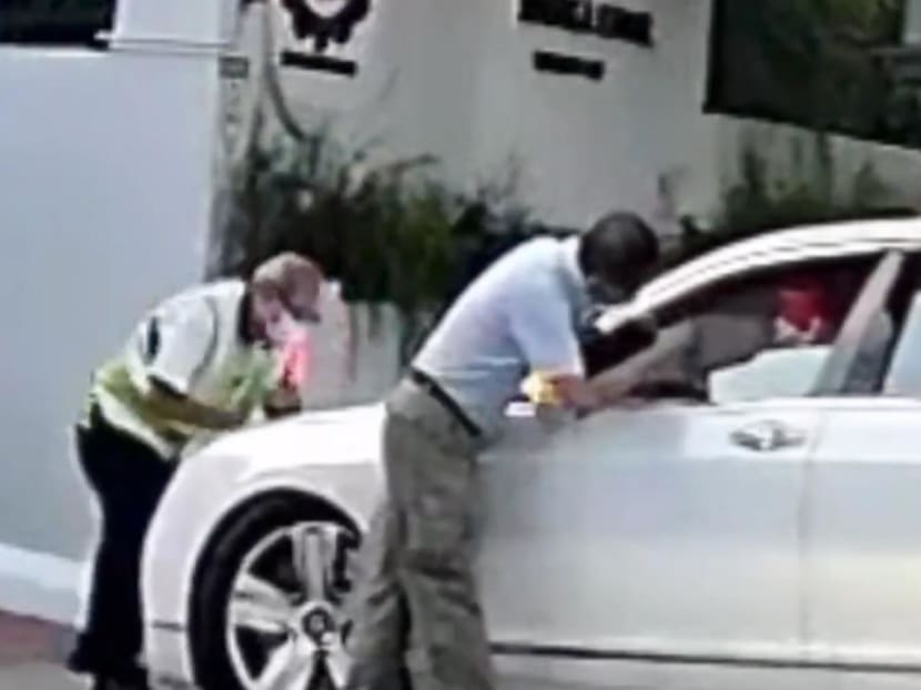 A screenshot from a video showing a security officer and a staff member of Red Swastika School preventing a car from entering the school compound.