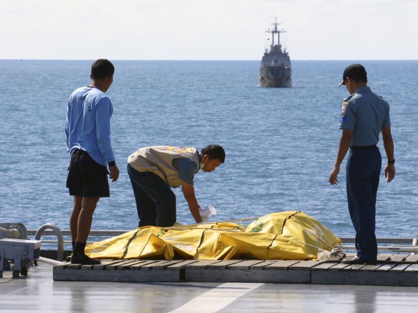 Crew members inspect body bags containing bodies believed to be of the victims of AirAsia Flight QZ 8501 on the deck of Indonesian Navy Ship KRI Banda Aceh, on the Java Sea, Indonesia, Jan 23, 2015. Photo: AP