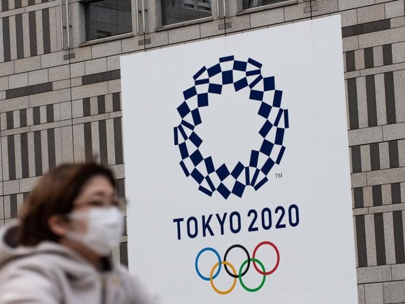 A woman wearing a face mask rides her bike in front of the Tokyo 2020 Olympic games logo outside the Tokyo Metropolitan Government Building on April 23, 2020. A woman wearing a face mask rides her bike in front of the Tokyo 2020 Olympic games logo outside the Tokyo Metropolitan Government Building on April 23, 2020.