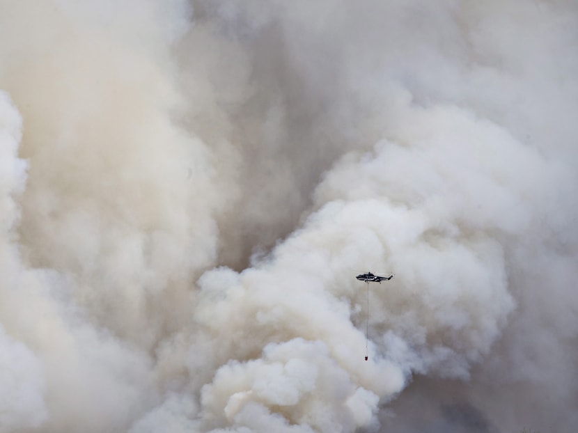 A helicopter battles a wildfire in Fort McMurray Alberta, on Wednesday, May 4, 2016. The raging wildfire emptied Canada's main oil sands city, destroying entire neighborhoods of Fort McMurray, where officials warned Wednesday that all efforts to suppress the fire have failed. Photo: The Canadian Press via AP