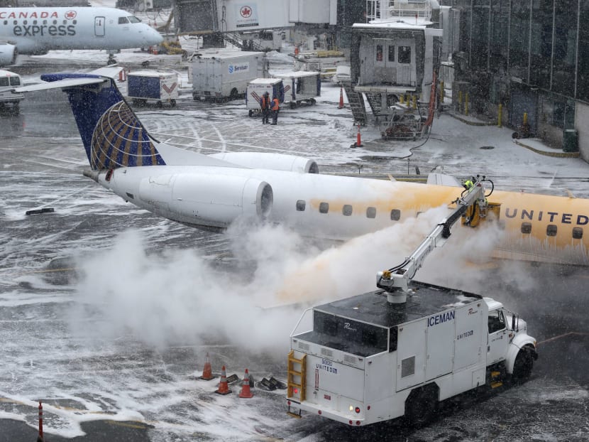 A man de-ices a plane during a light snow at a gate at LaGuardia Airport in New York, Jan 26, 2015. Photo: AP