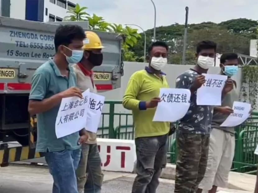 Workers at the industrial building NCS Hub Ang Mo Kio holding signs to demand for payment of owed salary from Shanghai Chong Kee on Oct 18, 2022.