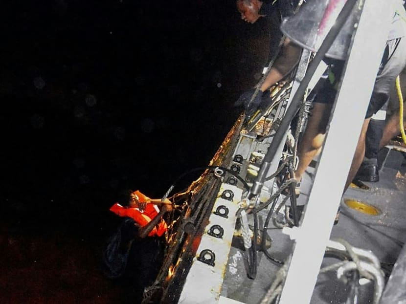 This handout photo taken on May 17, 2021 and released by the Indian Navy on May 18, 2021, shows Indian Navy personnel on board of the ship INS Kolkata rescuing a man from the life raft of the vessel Vara Prabha, after Cyclone Tauktae hit the west coast of India with powerful winds and driving rain, leaving at least 20 people dead.