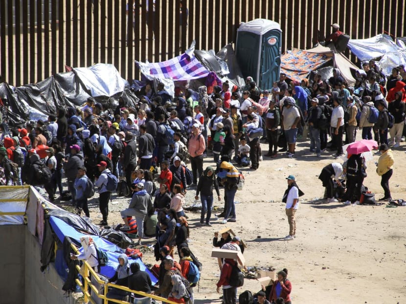 Migrants gather between the primary and secondary border fences in San Diego as the United States prepares to lift Covid-19 era restrictions known as Title 42, that have blocked migrants at the US-Mexico border from seeking asylum since 2020