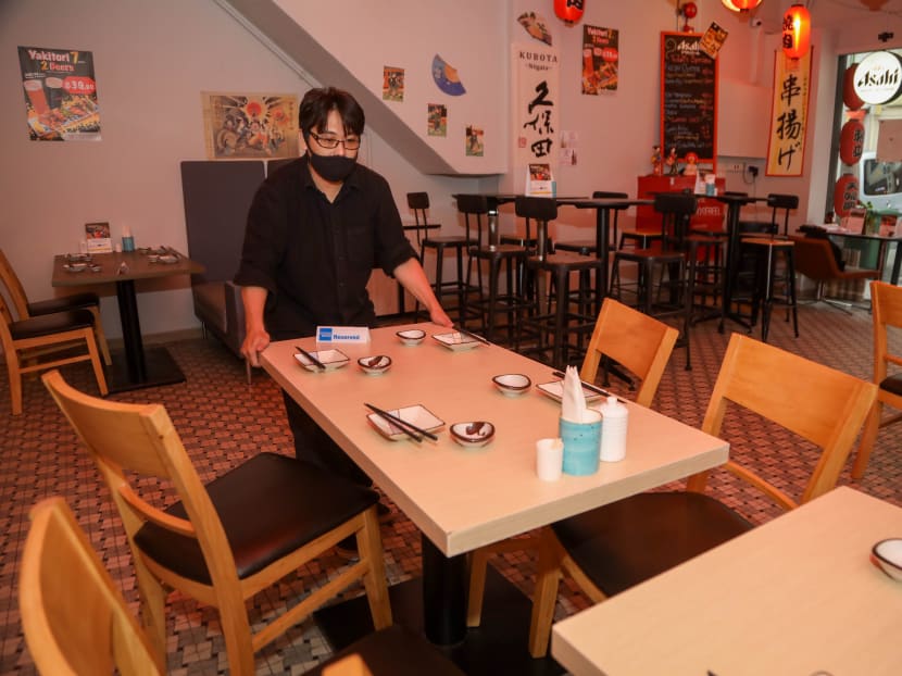 A worker at Hinode Izakaya and Bar separating tables that would normally seat up to eight.