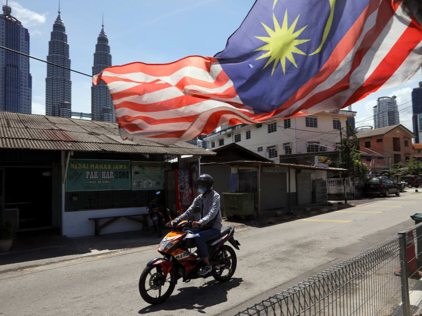 A man wearing a protective mask rides across a street, during a lockdown due to the Covid-19 outbreak, in Kuala Lumpur, Malaysia on Feb 2, 2021.