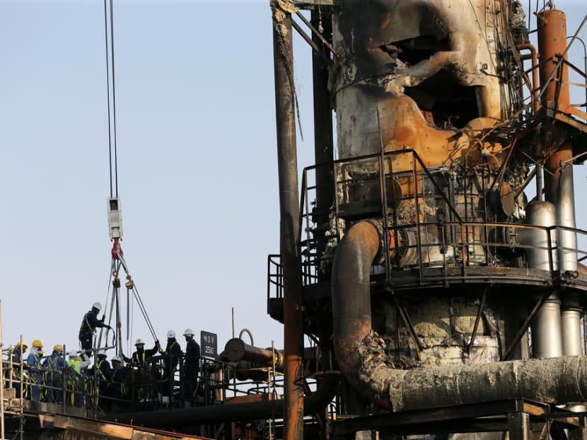 Workers are seen at the damaged site of Saudi Aramco oil facility in Abqaiq.