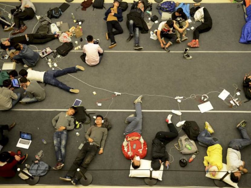 People sleep on the floor as they queue up for the opening of a new Apple Store in Hangzhou, Zhejiang province, China, April 24, 2015. Photo: Reuters