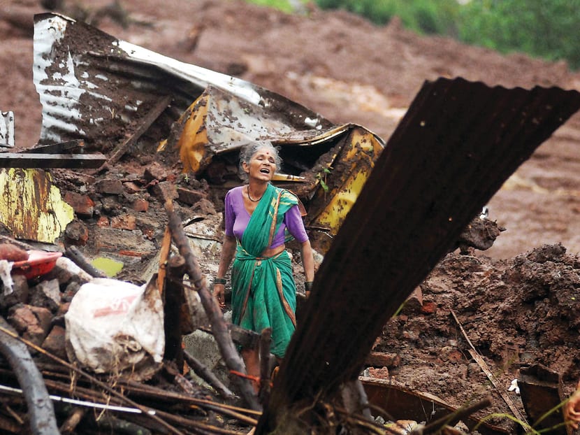 An Indian woman crying as she searches for her family members amid the debris of her home in Malin village in the western Indian state of Maharashtra. Photo: AP