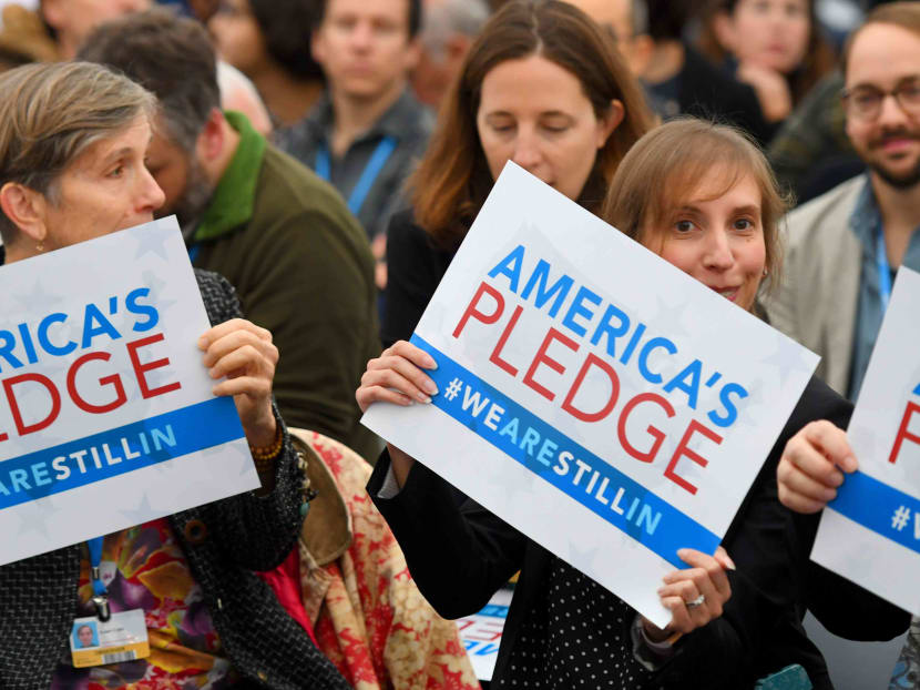 Visitors show posters reading “ America´s pledge - we are still in” during the COP23 United Nations Climate Change Conference in Bonn, Germany. Other leaders have taken up the climate leadership role after United President Donald Trump announced in June that the US would withdraw from the Paris agreement. Photo: AFP