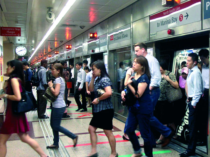Commuters step out of an MRT train at Raffles Place MRT Station. TODAY file photo