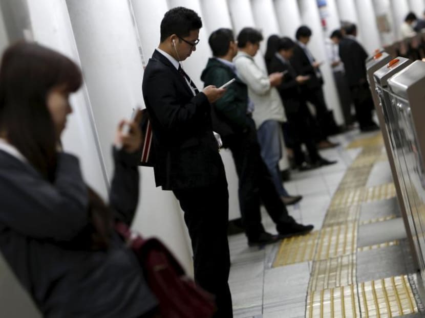 People look at their mobile phones while waiting for a train at a subway station in Tokyo, Japan, Oct 14, 2015. Photo: Reuters