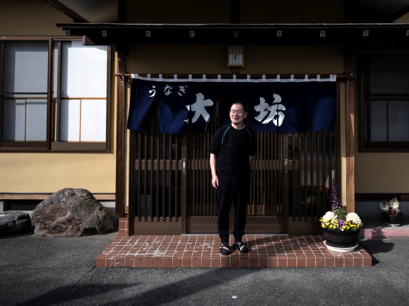 In this picture taken on March 1, 2021, local resident and manager of an eel restaurant Masakazu Daibo, who returned to his hometown last year and reopened the family restaurant established by his grandfather, poses outside the restaurant in Namie, Fukushima Prefecture.