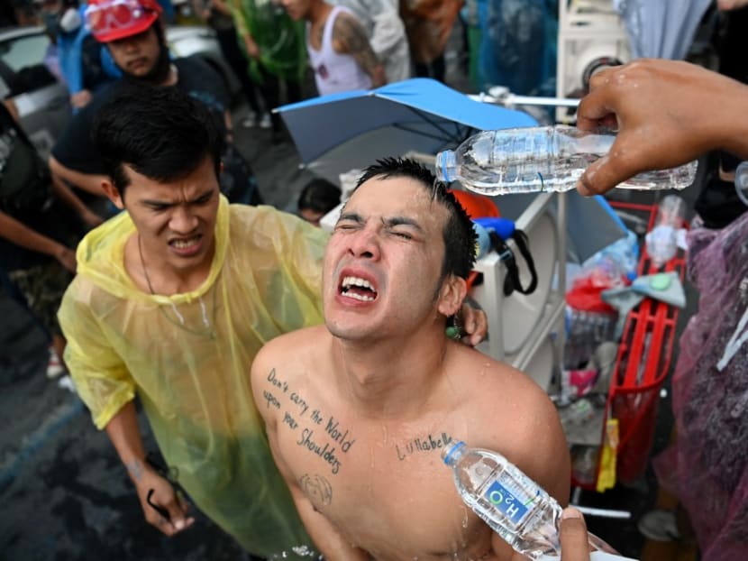 A pro-democracy protester has water poured on him after tear gas was fired during an anti-government rally in Bangkok on Tuesday, Nov 17, 2020.