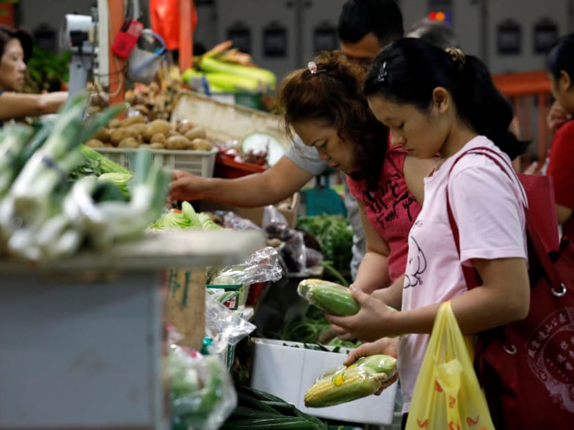 People shop for vegetables at a wet market in Singapore.