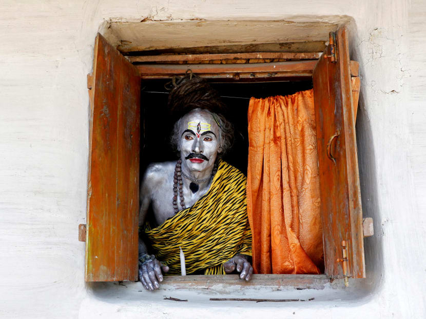 A devotee, dressed as Hindu God Shiva, looks out from a window as he waits to perform during the annual Shiva Gajan religious festival on the outskirts of Agartala, India.