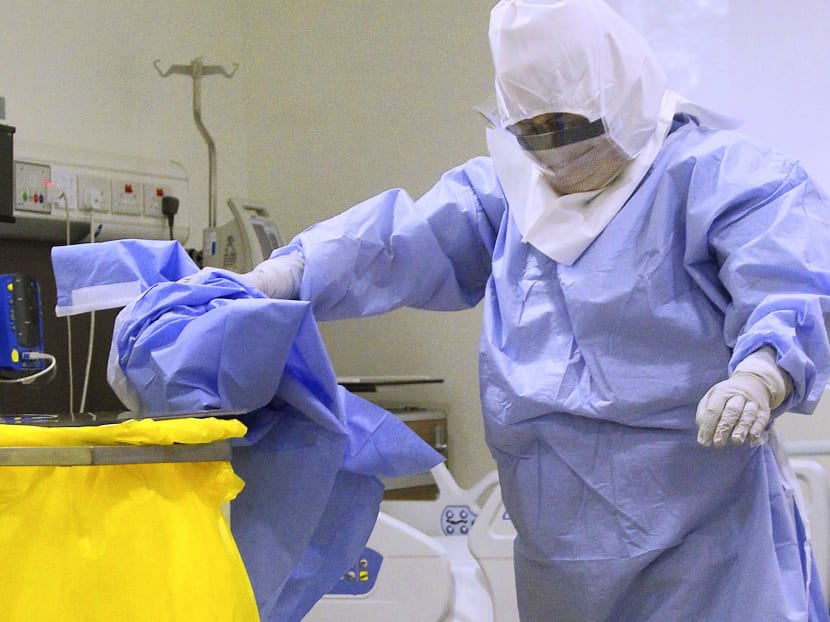Senior staff nurse Naw Hser Bwe demonstrates the proper steps to taking off the  Personal Protection Equipment (PPE) and disposing of it, Oct 24, 2014. Photo: Ernest Chua