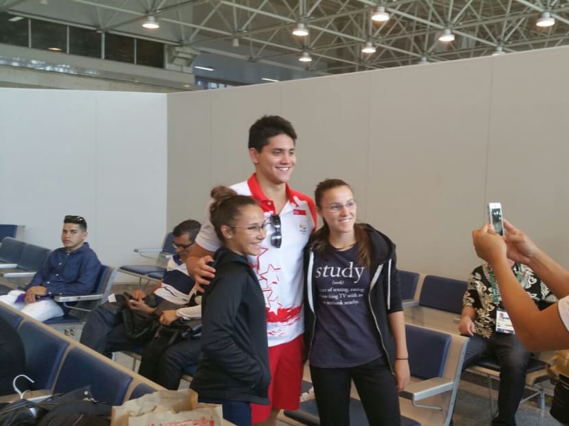 Joseph Schooling with fans at the Rio International Airport as Singapore National Olympic Council president Tan Chuan-Jin, who is also the Minister for Social and Family Development, helps to take photographs. Photo: Low Lin Fhoong