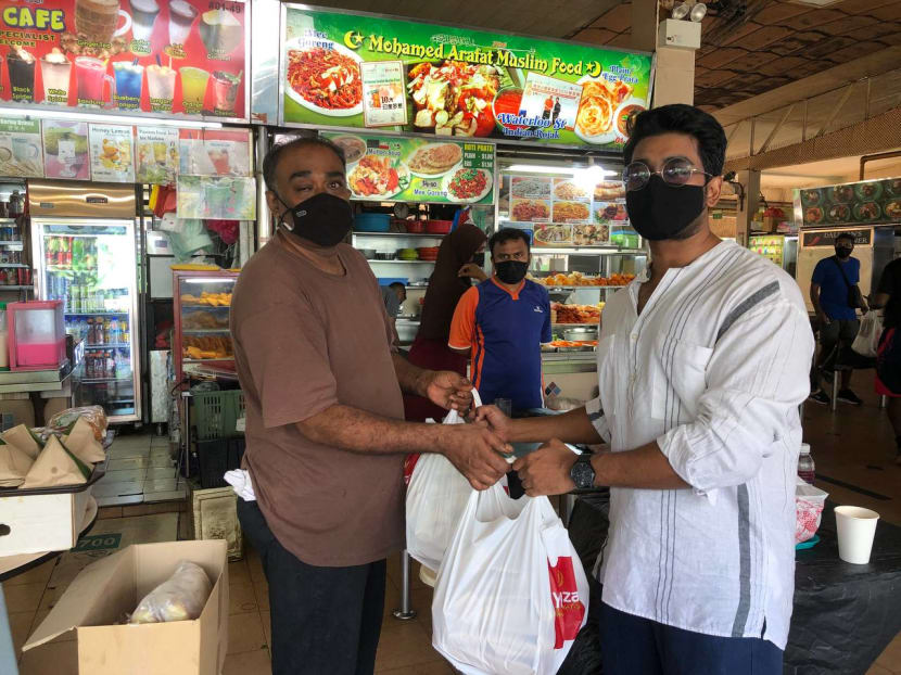 Musician Shabir Tabare Alam (right) collecting food from a hawker stall at Seah Im Food Centre to deliver to migrant workers as part of the WeEat initiative.