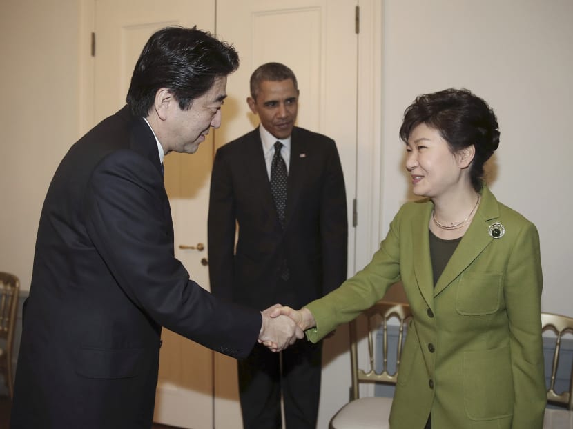 South Korean President Park Geun-hye (right) shakes hands with Japanese Prime Minister Shinzo Abe (left) as US President Barack Obama looks on before their trilateral meeting at the US Ambassador's Residence in the Hague, Netherlands, on March 25, 2014. Photo: AP