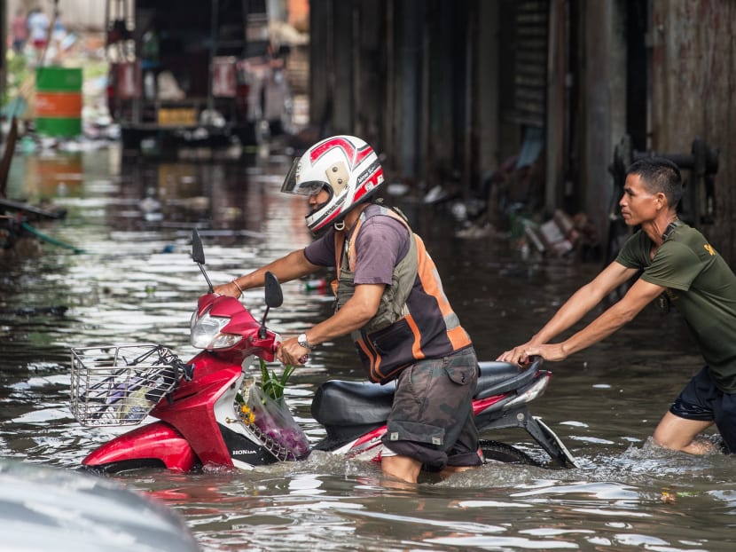 A man helps push a dead motorcycle taxi on a flooded street in Bangkok recently. Bangkok residents have lost faith in the government’s claims that it will prevent widespread flooding in the future. Photo: AFP