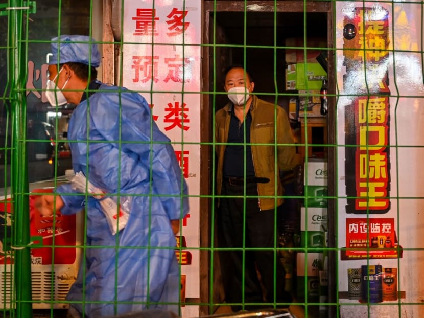 This photo taken late on Oct 7, 2022 shows a man looking on from a shop in a neighbourhood in lockdown as a worker erects fencing Shanghai's Changning district, after new Covid-19 cases were reported.
This photo taken late on Oct 7, 2022 shows a man looking on from a shop in a neighbourhood in lockdown as a worker erects fencing Shanghai's Changning district, after new Covid-19 cases were reported.