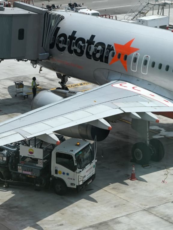 A refuelling truck is parked next to a Jetstar plane at Changi International Airport in Singapore on May 13, 2022.