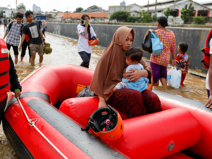 A woman holds a child as they are evacuated by an inflatable boat at an area affected by floods in Jakarta, Indonesia, on Jan 2, 2020.