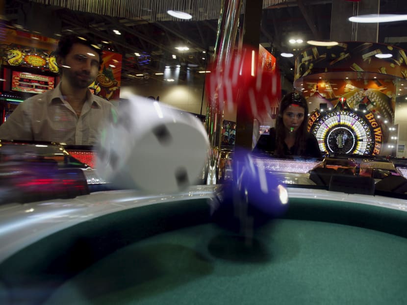 Visitors try a dice game at Gaming Expo Asia in Macau in this file photo.  Macau is expected to report gaming revenues this week.  Photo: Reuters