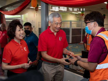 Prime Minister Lee Hsien Loong (centre) and National Trades Union Congress president Mary Liew distributing red packets to SMRT staff members during Mr Lee's Chinese New Year visit to the Woodlands Integrated Transport Hub on Jan 21, 2023.