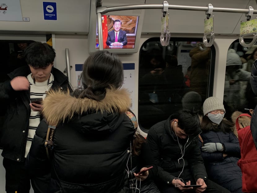Passengers are seen next to a screen broadcasting news of Chinese President Xi Jinping addressing a New Year's Eve speech, on a subway train in Beijing, China Dec 31, 2019.
