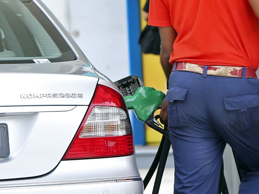 A man pumps petrol into a car at a petrol station. Photo: Ernest Chua