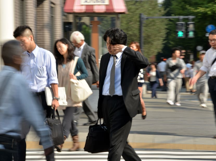 This file photo taken on Sep 30, 2014 shows a Japanese businessman rubbing his eyes as he heads to his office in Tokyo. Photo: AFP