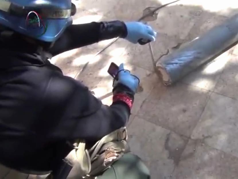 In this image taken from amateur video posted online, a presumed UN staff member measures and photographs a canister on Aug 26, 2013 in a Damascus suburb where the Syrian regime allegedly used deadly chemical weapons. Photo: AP