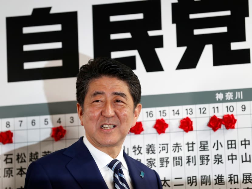 Japan's Prime Minister Shinzo Abe, leader of the Liberal Democratic Party (LDP), smiles as he puts a rosette on the name of a candidate who is expected to win the lower house election, at the LDP headquarters in Tokyo.Photo: Reuters